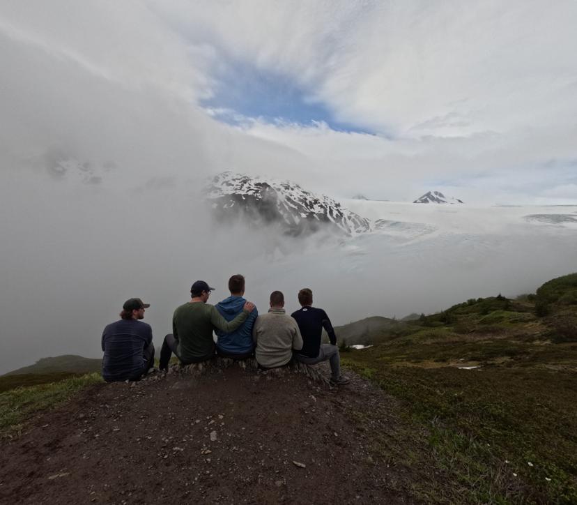 The crew sitting on a ridge above the clouds in Alaska